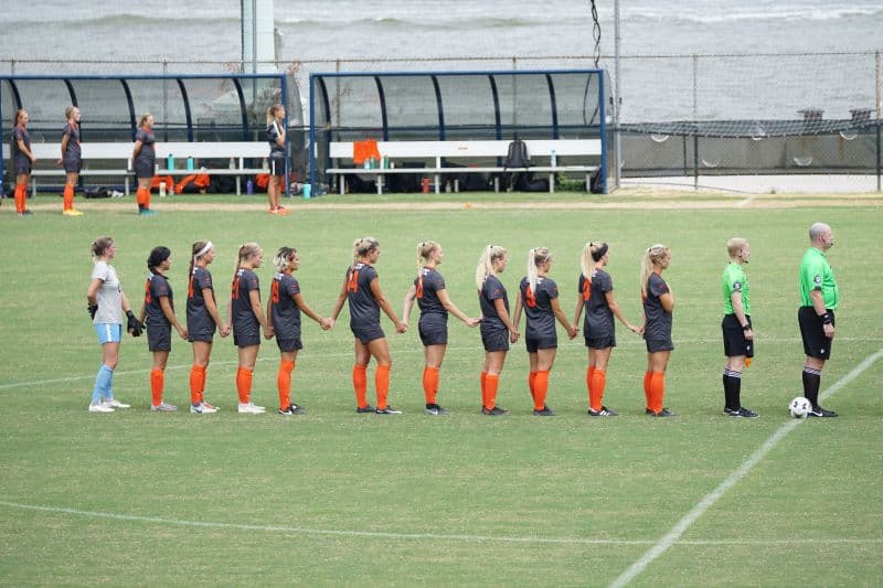 female soccer team lineup with referee before a game